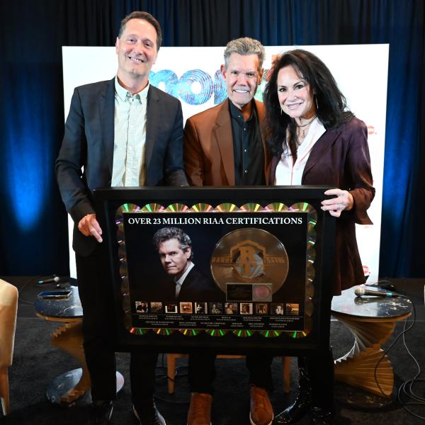 RANDY TRAVIS RECEIVES CAREER PLAQUE COMMEMORATING 23 MILLION CERTIFIED UNITS FROM RIAA CHAIRMAN & CEO MITCH GLAZIER AT MONDO.NYC